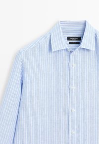 Chemise en lin bleu clair à manches longues avec des rayures verticales blanches et bleu foncé, devant boutonné et col pointu.