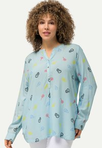 Camicia azzurra chiaro con bottone, caratterizzata da un motivo giocoso di icone di caramelle e gelati in vari colori. Realizzata in tessuto morbido con una vestibilità comoda.