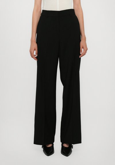 Black wide-leg trousers with a flat front, featuring a smooth texture and belt loops, paired with pointed black shoes.