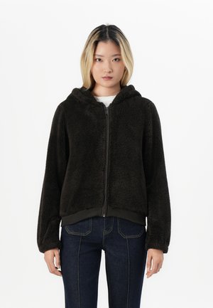 Brun fleece hettegenser med frontglidelås og hette, med en myk tekstur og elastisk kant, kombinert med mørke jeans.