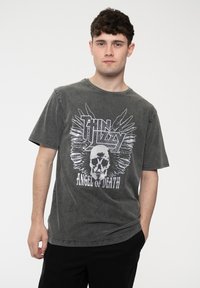 Gray graphic t-shirt featuring a skull design with wings, printed text "Thin Lizzy" and "Angel of Death," short sleeves, and a relaxed fit.