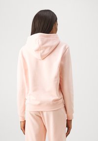 Felpa con cappuccio rosa, dotata di polsini e orlo a costine. Tessuto morbido e testurizzato. Cappuccio regolabile con coulisse e design con tasca a marsupio.
