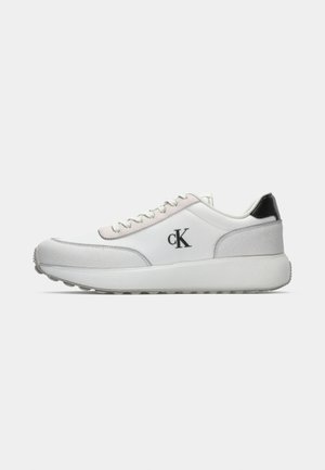 Calvin Klein baltos sportbačiai su lygiu odiniu viršumi, zomšos akcentais, juodu kulnu ir storu baltu padu. Logotipas šone.