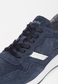 Sneaker in suede blu navy con lacci neri, striscia bianca laterale, design perforato e colletto imbottito. Presenta una suola in gomma bianca.