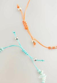 Justerbare armbånd i orange og turkis snor med sølvperler og små stens detaljer. Teksturerede knuder skaber lag-effekt.