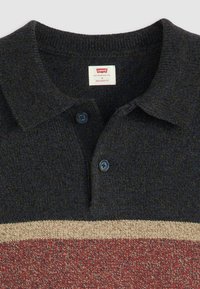 Knitted polo shirt in dark blue with a relaxed fit; features a textured fabric, two dark buttons, and a striped pattern in beige and rust.