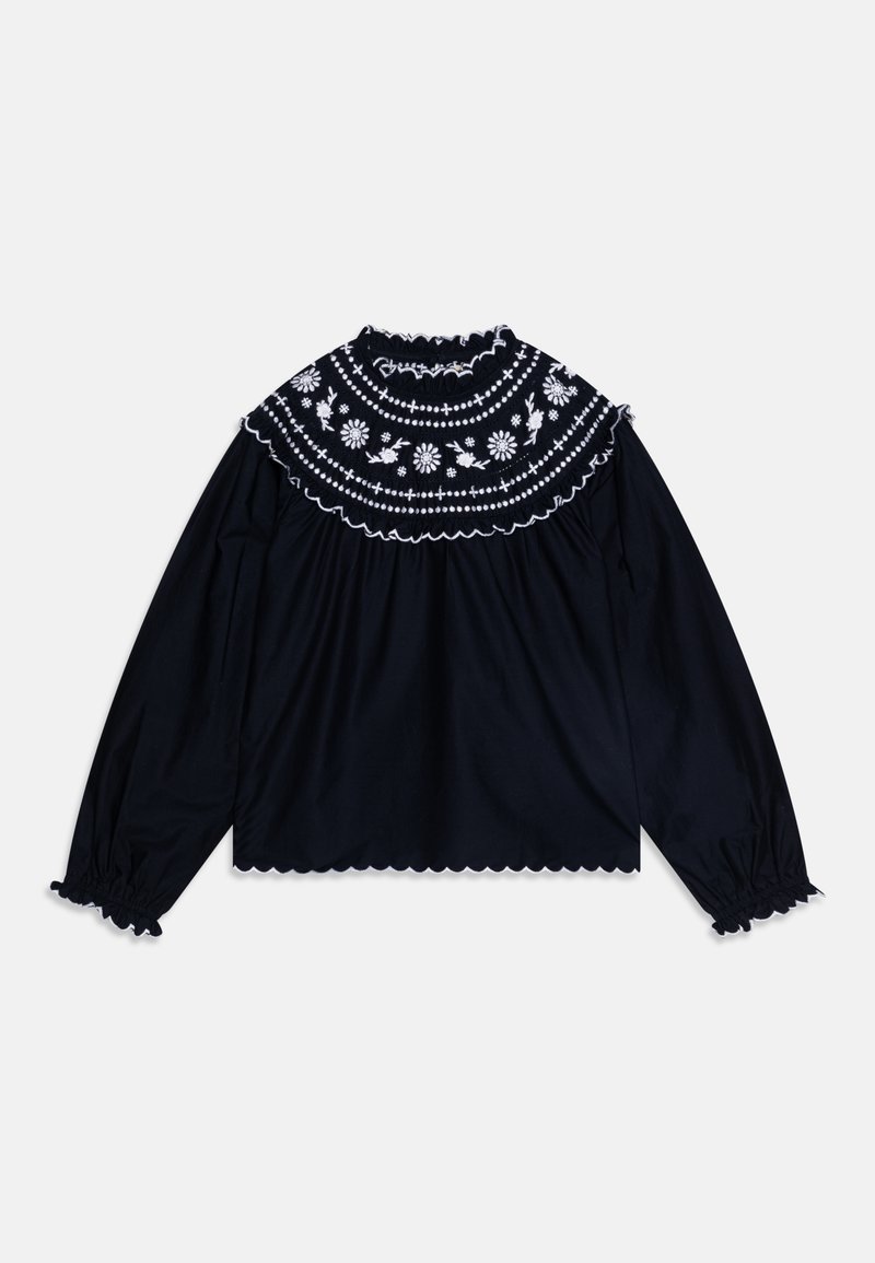 Svart langermet bluse med volangkrage som har hvit blomsterbroderi og scalloped kantdetaljer. Myk bomullsmateriale tekstur.