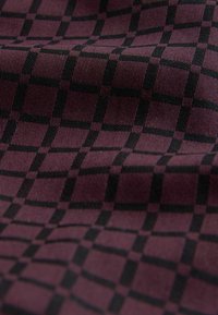 Textil mit einem gewebten Muster aus schwarzen Karos auf einem tiefburgunderfarbenen Hintergrund, mit einer glatten Textur und leichtem Glanz.