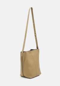 Tan läder tote-väska med en strukturerad finish, vertikal sömdetalj och en justerbar rem, som har en öppen toppdesign.