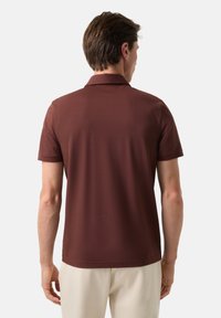 Hnědý polokošile s krátkým rukávem vyrobená z hladkého materiálu, s klasickým límečkem a uvolněným střihem, s minimem švů a bez vzorů.