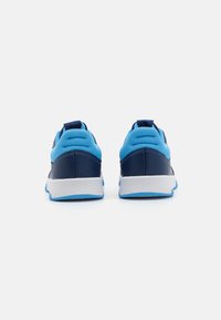 Des chaussures de sport bleues avec une tige en maille, des accents bleu marine et une semelle blanche. Elles présentent une finition texturée et une languette au talon.