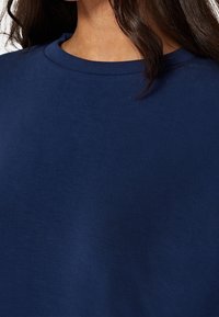 T-shirt blu navy con colletto a giro e maniche corte, realizzato in tessuto morbido con una texture liscia. Design minimalista, senza fantasie o dettagli.