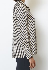 Camicia a maniche lunghe con un motivo a rombi beige e navy, con colletto button-down e spacchi laterali all'orlo per facilitare i movimenti.