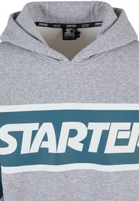 Sudadera gris con capucha y un gran logo en blanco y verde azulado de "STARTER" en el pecho. Textura suave, diseño casual y con capucha ajustable.