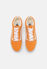Para jaskrawo pomarańczowych zamszowych trampek z białymi sznurówkami i paskiem po bokach, widziana z góry na białym tle.