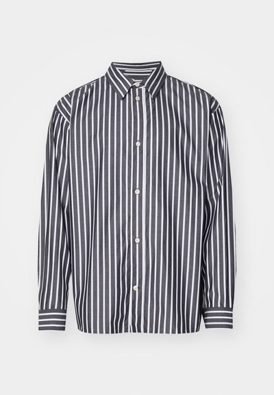 Camisa de botão às riscas com colarinho. Cor base escura com riscas verticais brancas. Mangas longas com padrões de punhos contrastantes.