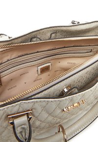 Borsa a sacca beige trapuntata con hardware dorato, scomparti interni e etichetta con logo. Rivestita in tessuto satinato con un motivo a monogramma.