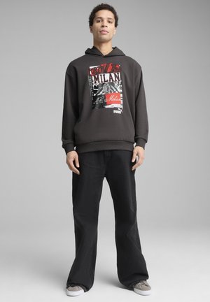 Mørkegrå hætte sweatshirt med et grafisk print, der viser "Forza Milan" med fed skrift. Kombinationen er med sorte bukser og grå sneakers.