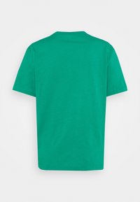 En enfärgad grön kortärmad t-shirt i bomull sedd bakifrån på en vit bakgrund.