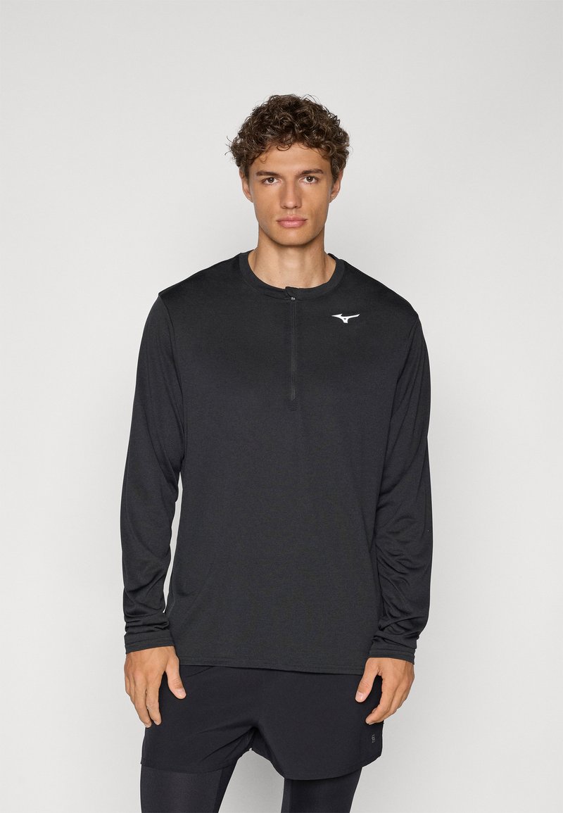 Svart langermet sporty topp med kvart glidelås og logo på brystet. Laget av lett materiale med en glatt tekstur.