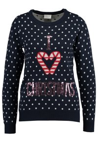 Pull marin à pois blancs, avec un design de cœur rayé rouge et blanc, et "CHRISTMAS" en sequins. Poignets et ourlet côtelés.