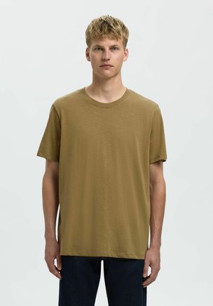 Olivengrøn T-shirt med korte ærmer og rund hals, lavet af blød, struktureret stof; afslappet pasform; båret med mørkeblå jeans.