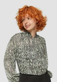 Transparante blouse in groen en grijs met een abstract patroon, mandarin kraag en knopen aan de voorkant. Heeft lange mouwen met gathered manchetten.