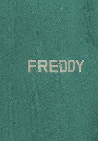 Tessuto di cotone turchese con la parola "FREDDY" stampata in digitale di un beige chiaro, centrata e in lettere capitolari, con una texture liscia.