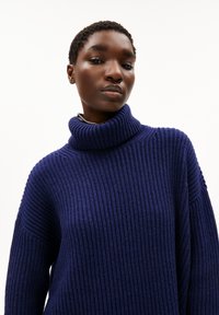 Navy-blauer, gerippter Pullover mit hohem Stehkragen, lässiger Passform und überschnittenen Schultern, aus einem strukturierten Strickstoff gefertigt.