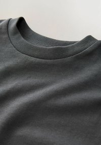 Dunkelgrauer Pullover mit geripptem Rundhalsausschnitt und glattem, strukturiertem Stoff, der sein einfaches und modernes Design zur Geltung bringt.