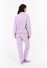 Paarse, gestructureerde fleece pyjama set met een ritsjack en een broek met een elastische tailleband. Beschikt over een verhoogd patroon en geribde manchetten.