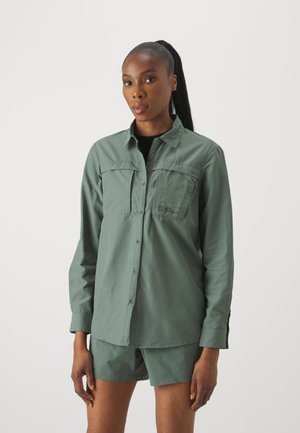 Lichtgroen overhemd met lange mouwen, twee borstzakken, knoopsluiting aan de voorkant en een zacht materiaal, gecombineerd met bijpassende shorts.