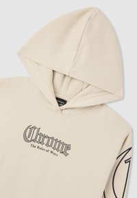 Beżowa bluza z kapturem z czarnym tekstem w stylu gotyckim "Chrome" oraz mniejszym napisem "The Ruler of Ways" na klatce piersiowej, a także okrągłą grafiką na rękawie.