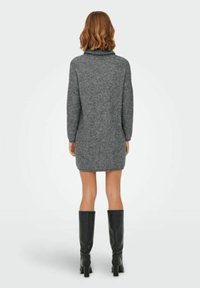 Rochie tricotată gri cu guler înalt, mâneci lungi și o croială relaxată, asortată cu cizme negre până la genunchi.
