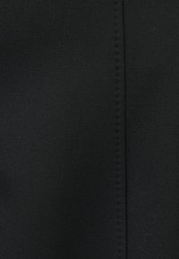 Čierna tkanina s hladkou textúrou a stredovým švom. Materiál pôsobí pevne tkaný s matným povrchom.