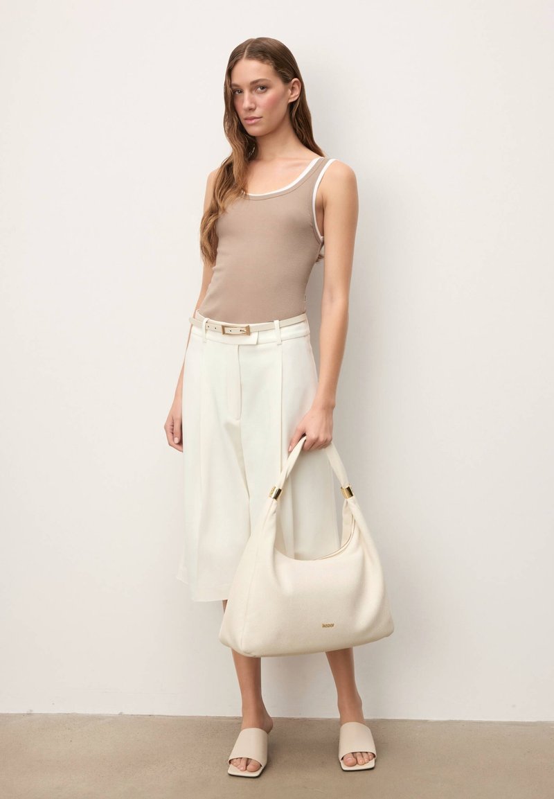 Débardeur beige avec bordure blanche, culottes blanches taille haute, sac à main crème avec ferrures dorées, et sandales légères beige clair sans lacets.