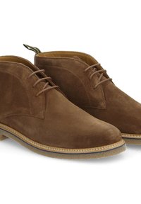 Bottines en daim marron avec une texture lisse, bout rond et fermeture à lacets. Présentent une semelle en caoutchouc contrastante et des détails de couture élégants.