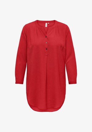 Sarkana garā piedurkņu tunika ar apaļu kakla izgriezumu, pogu priekšpusi un teksturētu audumu. Tam ir izliekta apakšmalas un plisētas detaļas.