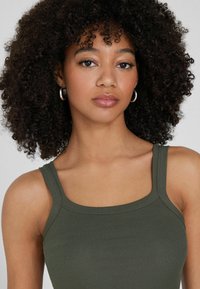 Olivgrünes, geripptes Tanktop mit quadratischem Ausschnitt und dünnen Trägern, aus einem strukturierten Stoff und mit figurbetontem Schnitt.