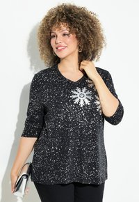 Maglietta nera a maniche lunghe con scollo a V, design di fiocchi di neve argentati e un motivo spruzzato. Tessuto morbido con vestibilità rilassata.
