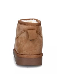 Stivale alla caviglia in suede marrone con una finitura texturizzata, rivestimento morbido visibile nella parte superiore e un occhiello in stoffa sul retro. Suola piatta in gomma.