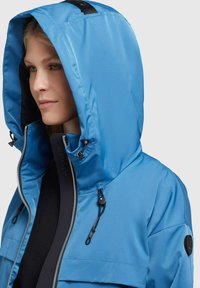Blue waterproof jacket with a detachable hood, zipper closure, adjustable drawstrings, and a black accent logo on the sleeve.