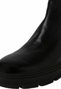 Černá kožená kotníková obuv s hladkým povrchem, zaoblenou špičkou a silnou černou gumovou podrážkou s dezénem pro lepší přilnavost.