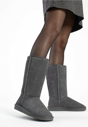 Gray suede knee-high boots with a soft texture, featuring contrast stitching and a flat rubber sole. The design is simple and functional.