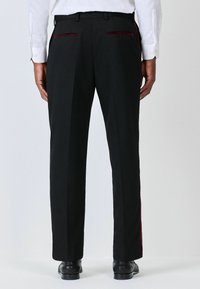 Schwarze maßgeschneiderte Hosen mit zwei Gesäßtaschen, die burgunderfarbene Akzente aufweisen, und einem geraden Schnitt. Kombiniert mit schwarzen Schuhen, von hinten gezeigt.