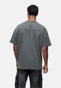 Grijze, oversized t-shirt van katoen met korte mouwen, een ronde hals en een gladde textuur. Zichtbare stiksels langs de schouders.