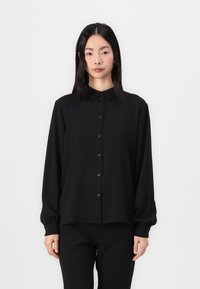 Black long-sleeve shirt with a collar, featuring a straight cut, button closure, and smooth texture. Worn with matching black pants.