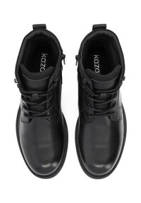 Mustad mustad nahast sokkidega jalatseid hõlbustamiseks, pehmendusega krae, lame tall ja õrn logo detail keele ja külje peal.