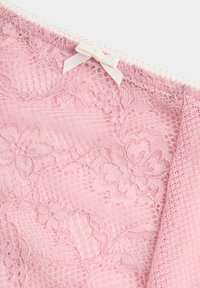 Růžová krajková látka s květinovými vzory a malou bílou stuhou na horním okraji.