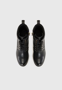 Black leather ankle boots feature a rounded toe, gold eyelets, and lace-up design with zipper. Smooth texture and ankle height.
